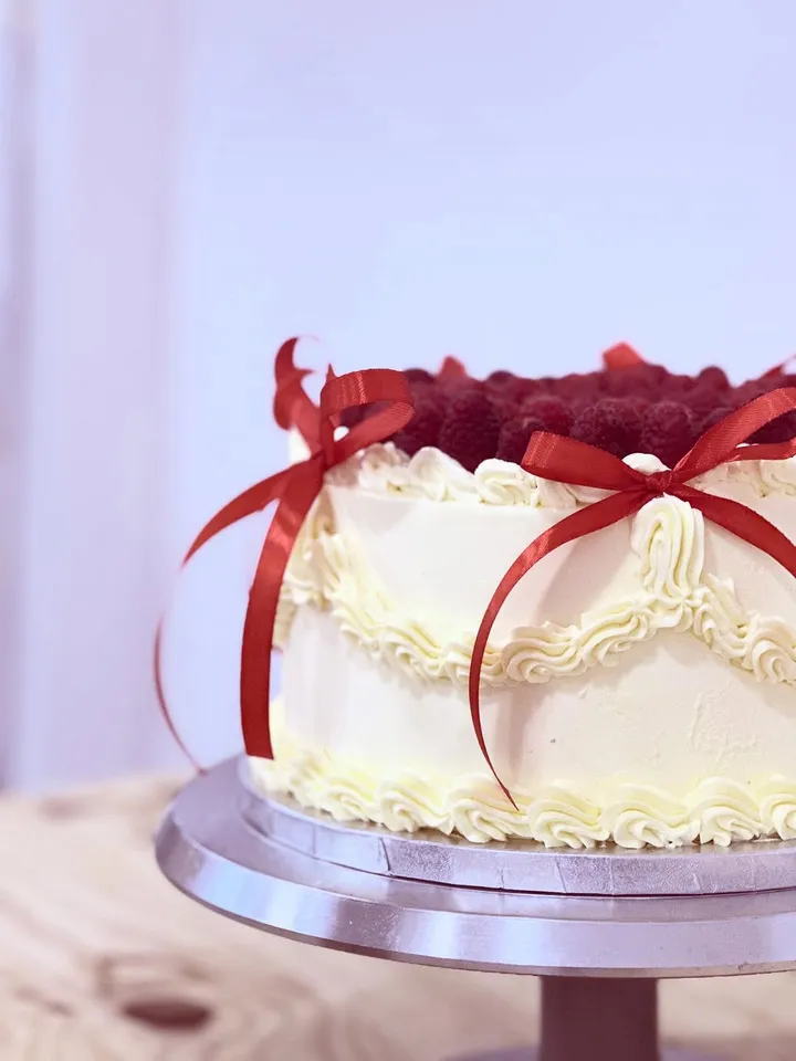 Tarta vintage blanca con lazos rojos y frambuesas